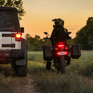 DENALI T3 modular LED rear signal pods glowing red on a motorcycle at sunset.