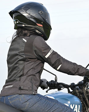 Motodrift ViaTerra Ellis women's black motorcycle riding jacket with reflective details worn by a rider on a bike