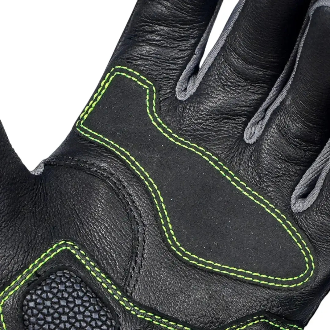 Close-up of a black leather glove with green stitching on a white background