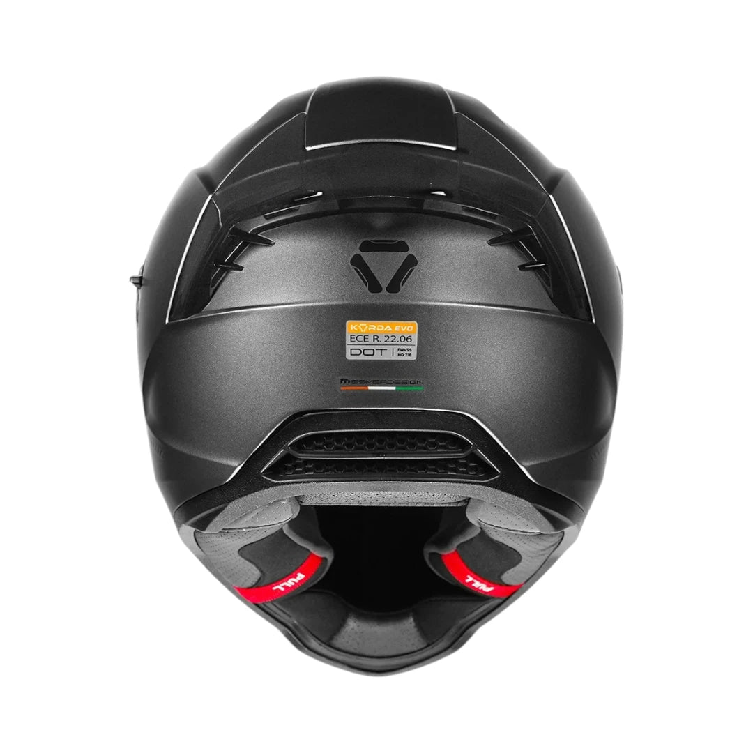 Motodrift Korda Evo Solid full face motorcycle helmet in matte black, rear view showing ventilation and safety labels.