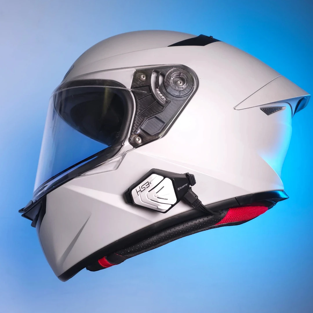 Motodrift BluArmor HS3 Bluetooth headset mounted on the side of a white full-face motorcycle helmet