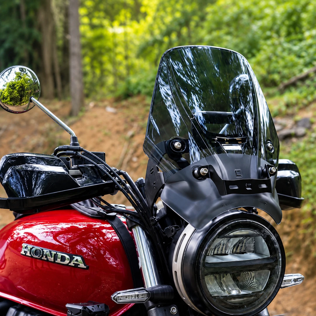 Carbon Racing BOLT smoked windscreen installed on a red Honda CB 350 RS motorcycle in a forest setting.