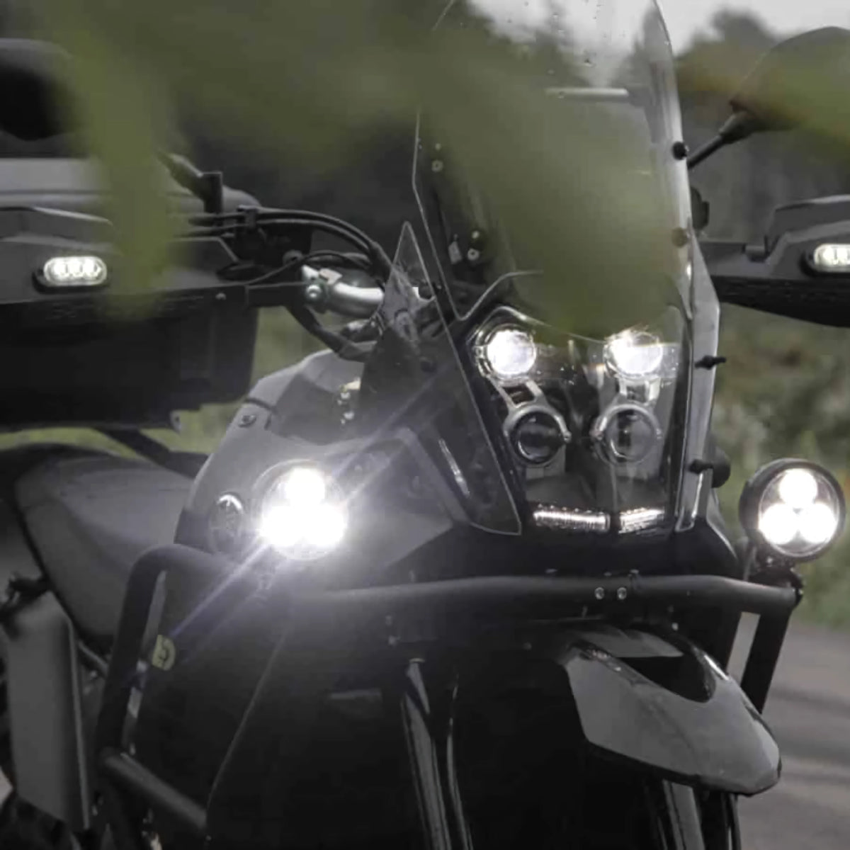 DENALI D3 LED driving lights mounted on a motorcycle front end, showing bright spot beam illumination.