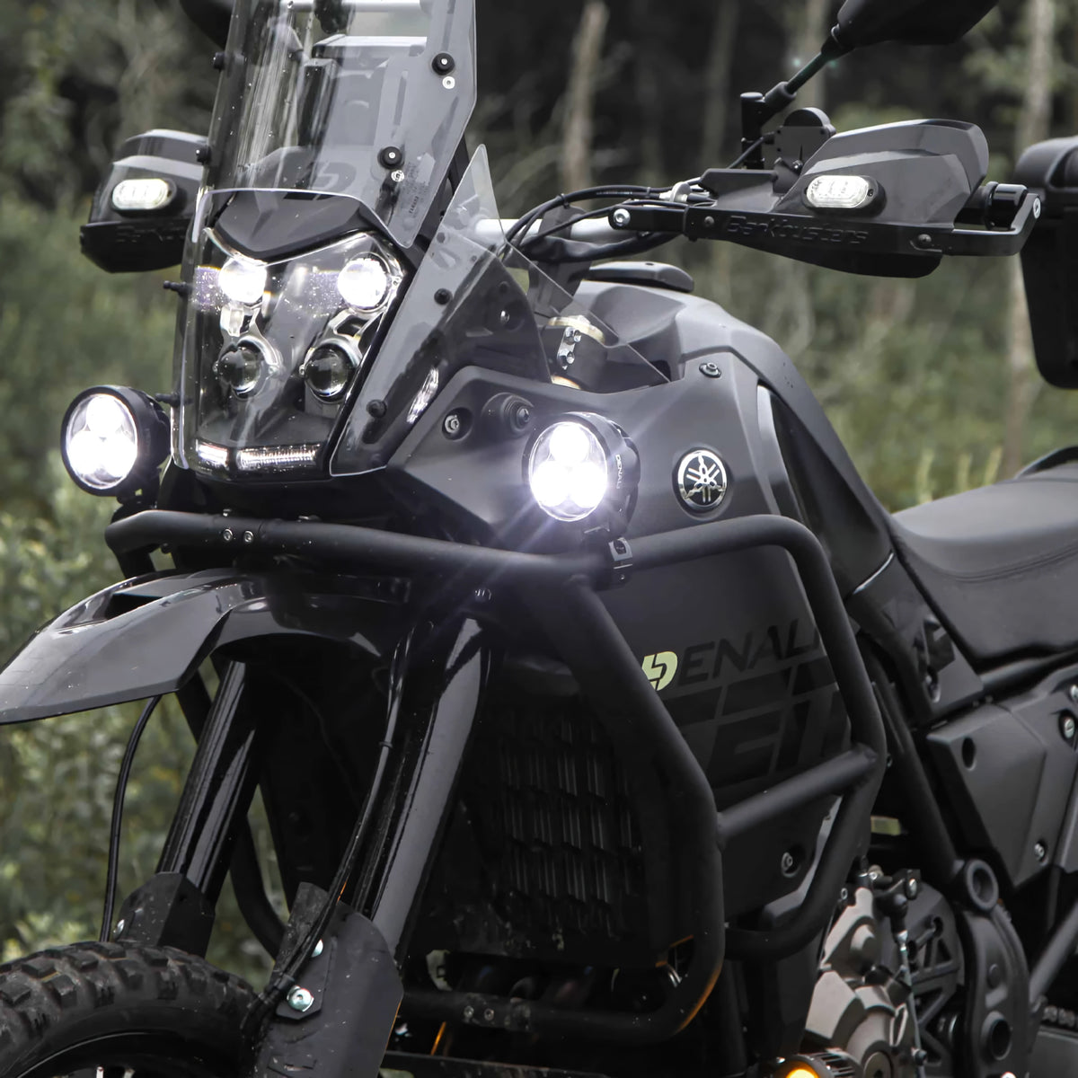 DENALI D3 LED driving lights mounted on a black adventure motorcycle, showing bright spot beam illumination.