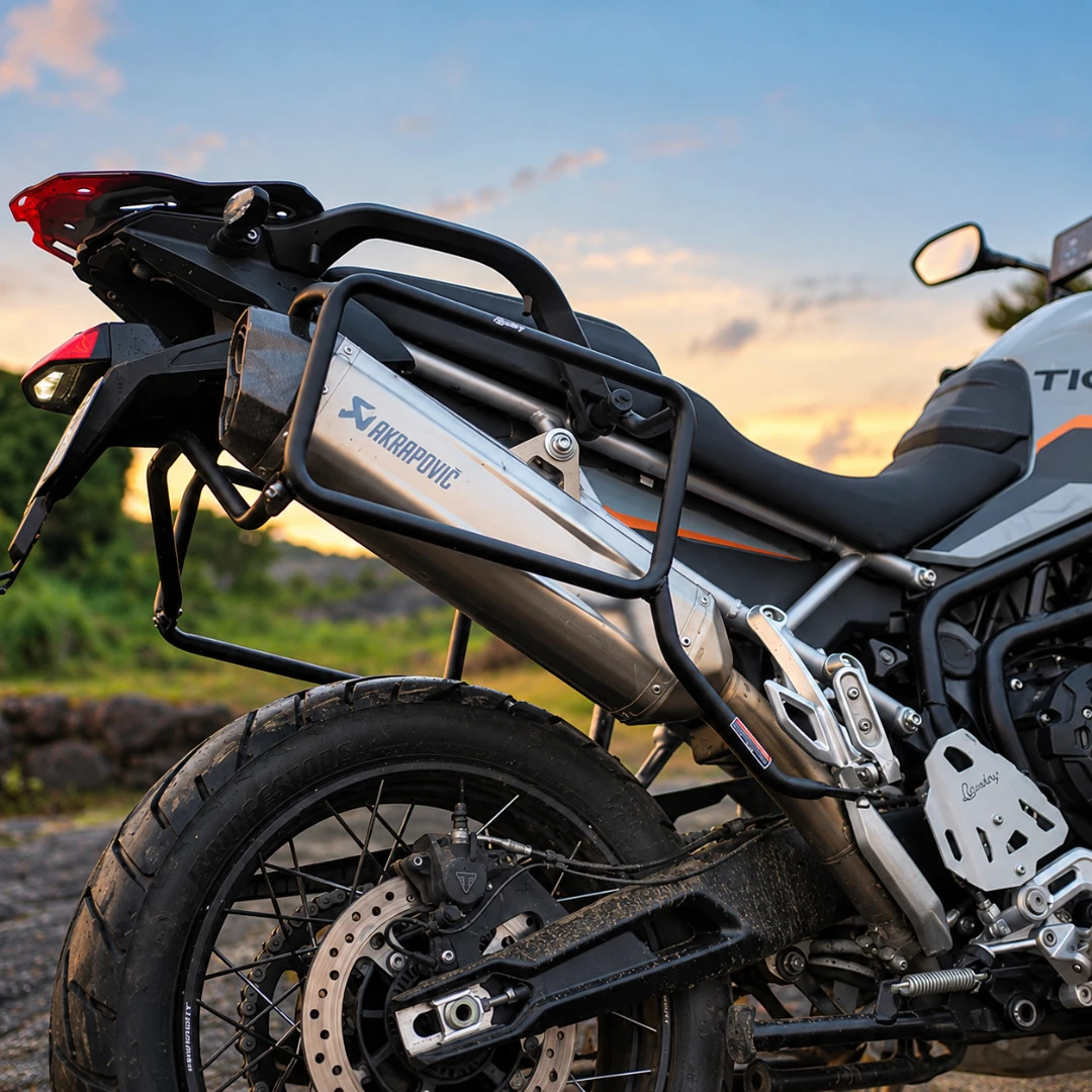 Legundary Fort Knox side box mount installed on a Triumph Tiger 900 motorcycle with an Akrapovic exhaust.
