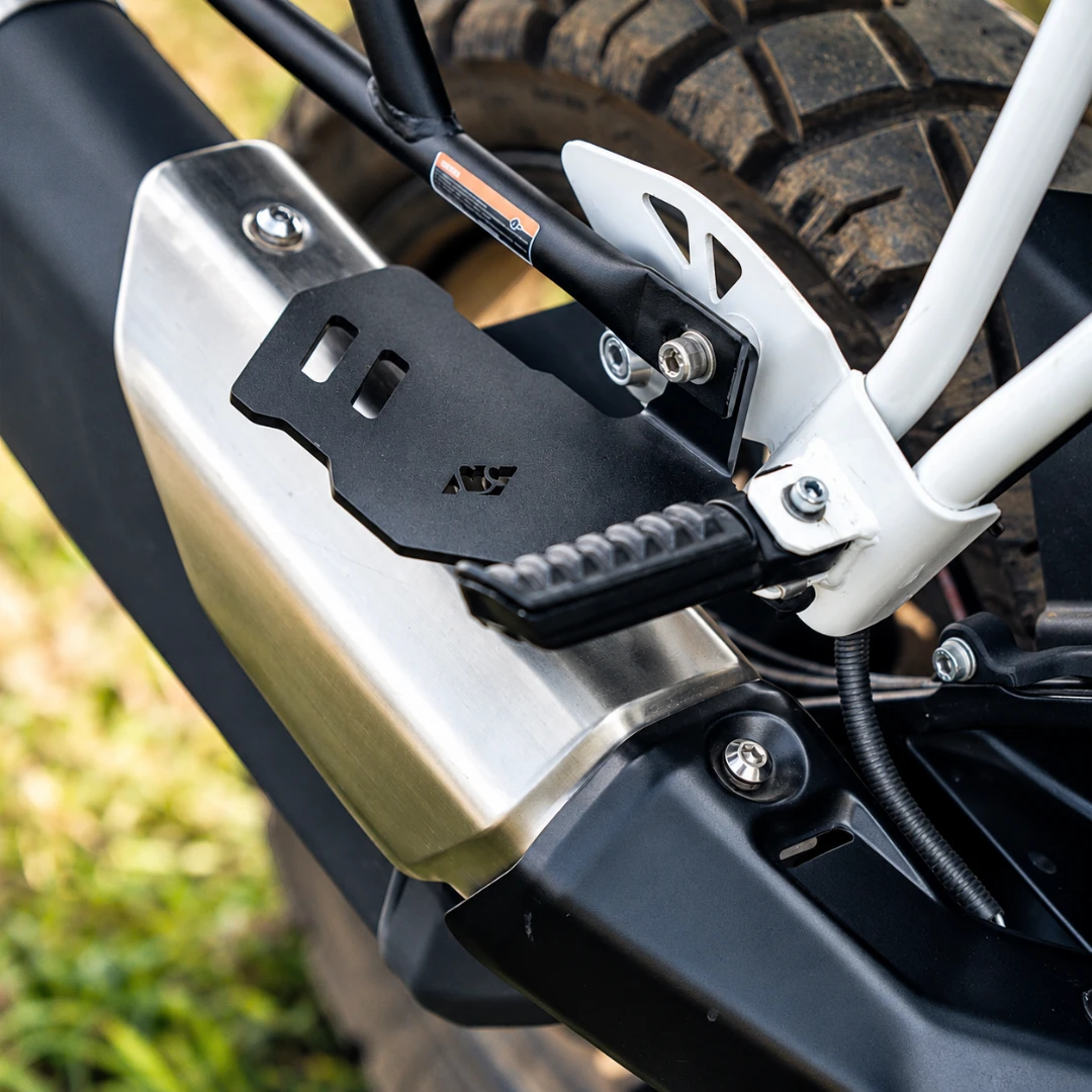 Black steel bolster pillion footrest installed on a TVS Apache RTX 300 motorcycle for passenger support
