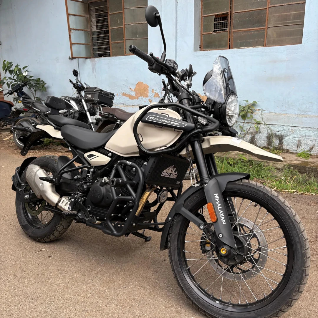 Black tubular steel crash guard with slider installed on a beige Royal Enfield Himalayan 450 motorcycle.