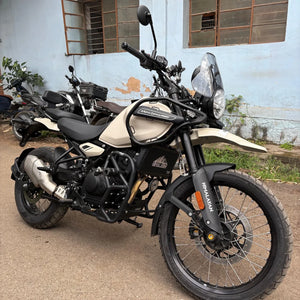 Black tubular steel crash guard with slider installed on a beige Royal Enfield Himalayan 450 motorcycle.
