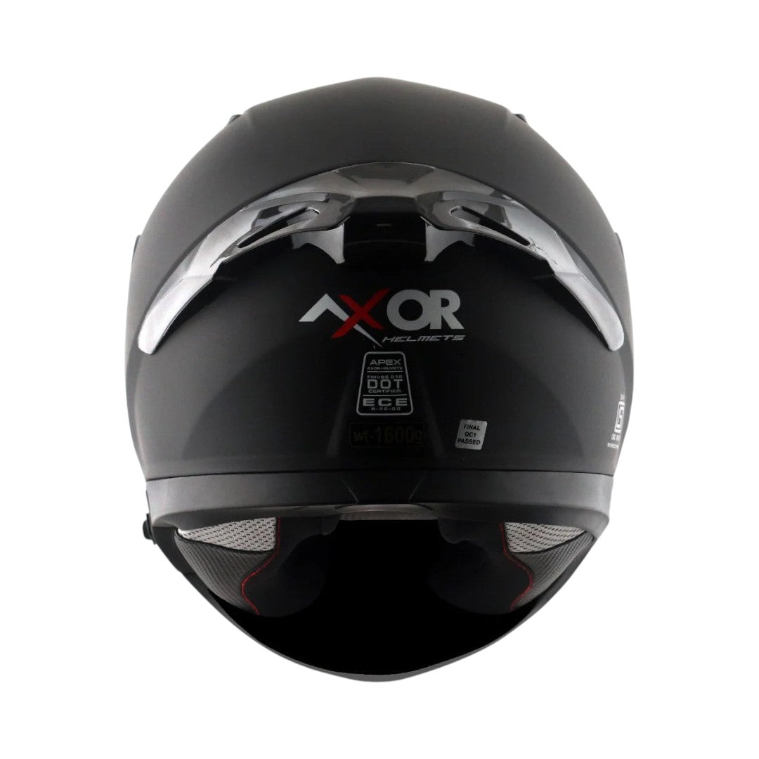 Motodrift Axor Apex solid matte black full-face motorcycle helmet, rear view showing safety certification labels.