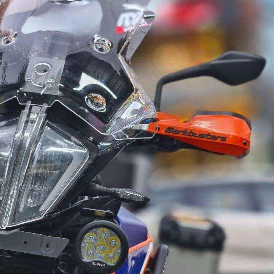 Motodrift Barkbusters orange handguards with two-point mounting hardware installed on a motorcycle handlebar