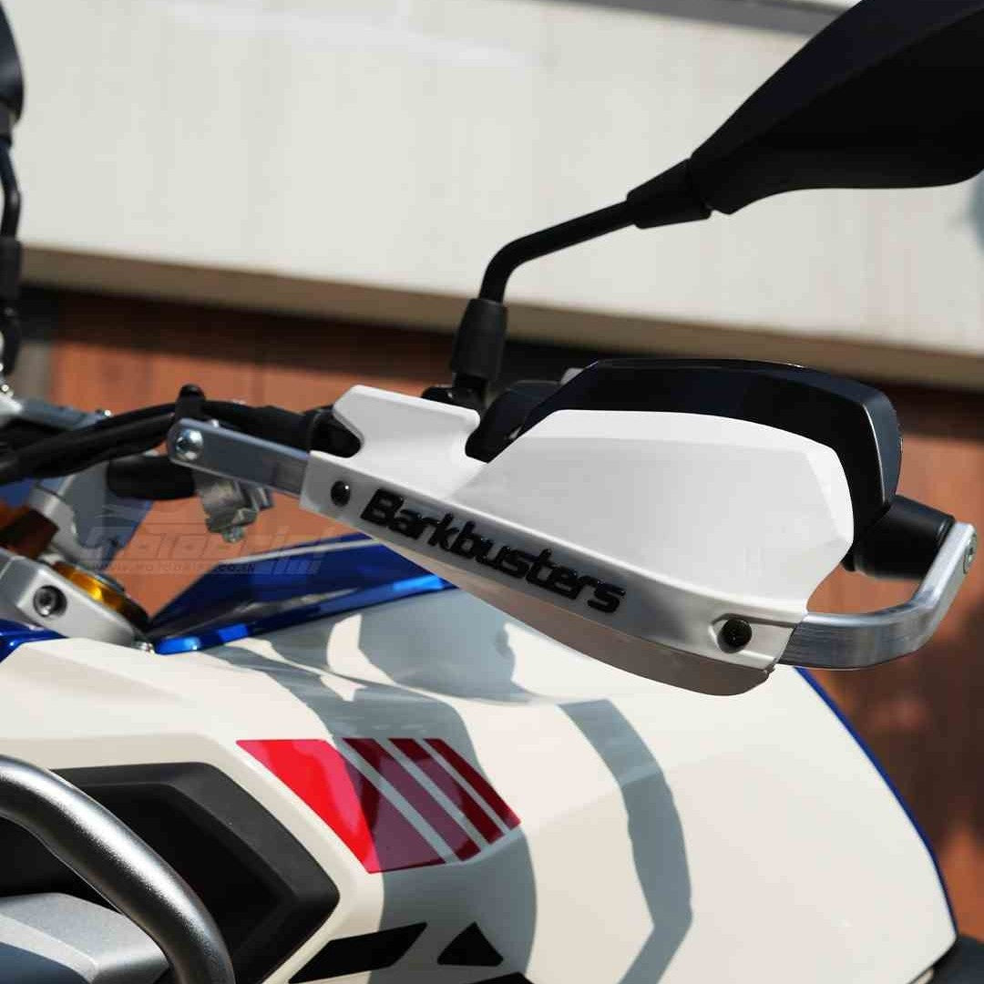 Motodrift Barkbusters two-point mount handguard kit with white plastic guard installed on a motorcycle handlebar