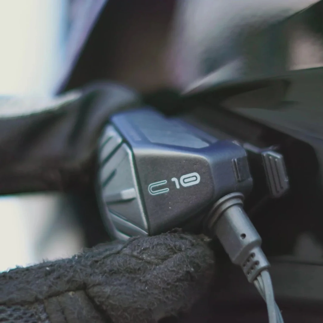 Motodrift BluArmor C10 Bluetooth motorcycle intercom mounted on a helmet with a charging cable connected