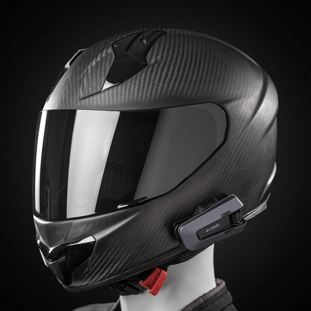 Motodrift Cardo Packtalk Edge motorcycle communication system mounted on a black carbon fiber full-face helmet