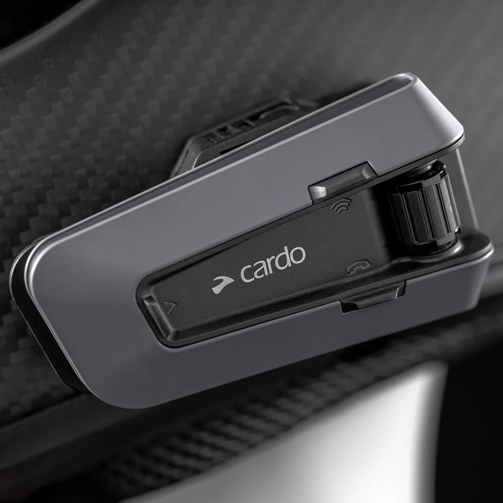 Motodrift Cardo Packtalk Edge motorcycle communication system mounted on a helmet with a sleek black design.