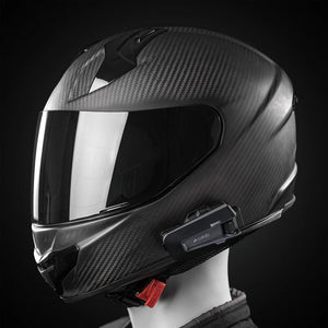 Motodrift Cardo Packtalk Neo motorcycle intercom mounted on a black carbon fiber helmet against a dark background