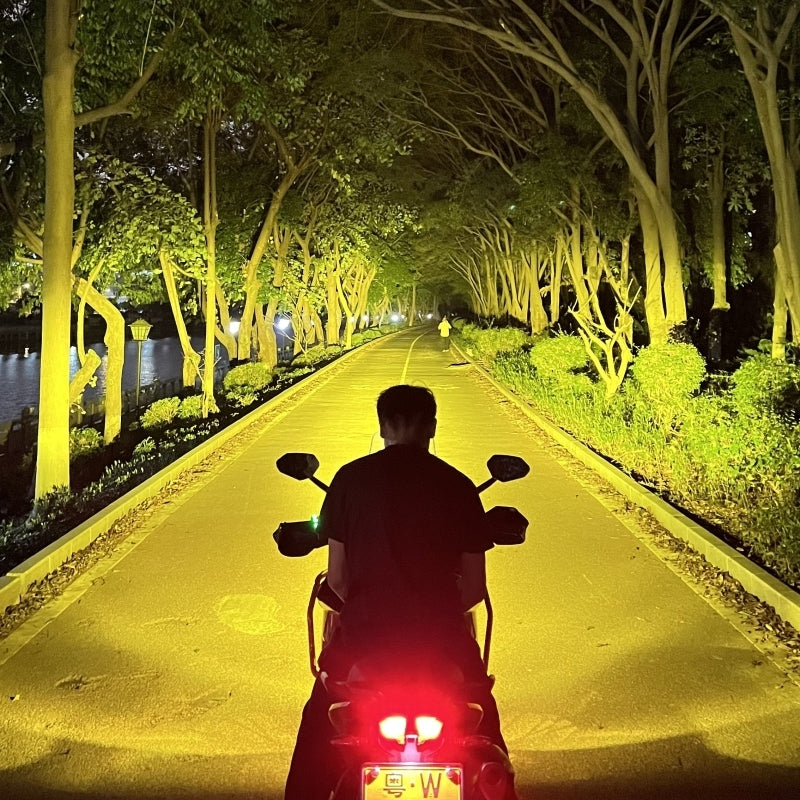 Motodrift Future Eyes Z4 auxiliary lights illuminating a dark tree-lined road with a powerful yellow beam