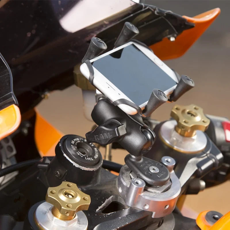 Motodrift RAM fork stem mount hardware pack installed on a motorcycle handlebar with a smartphone holder attached.