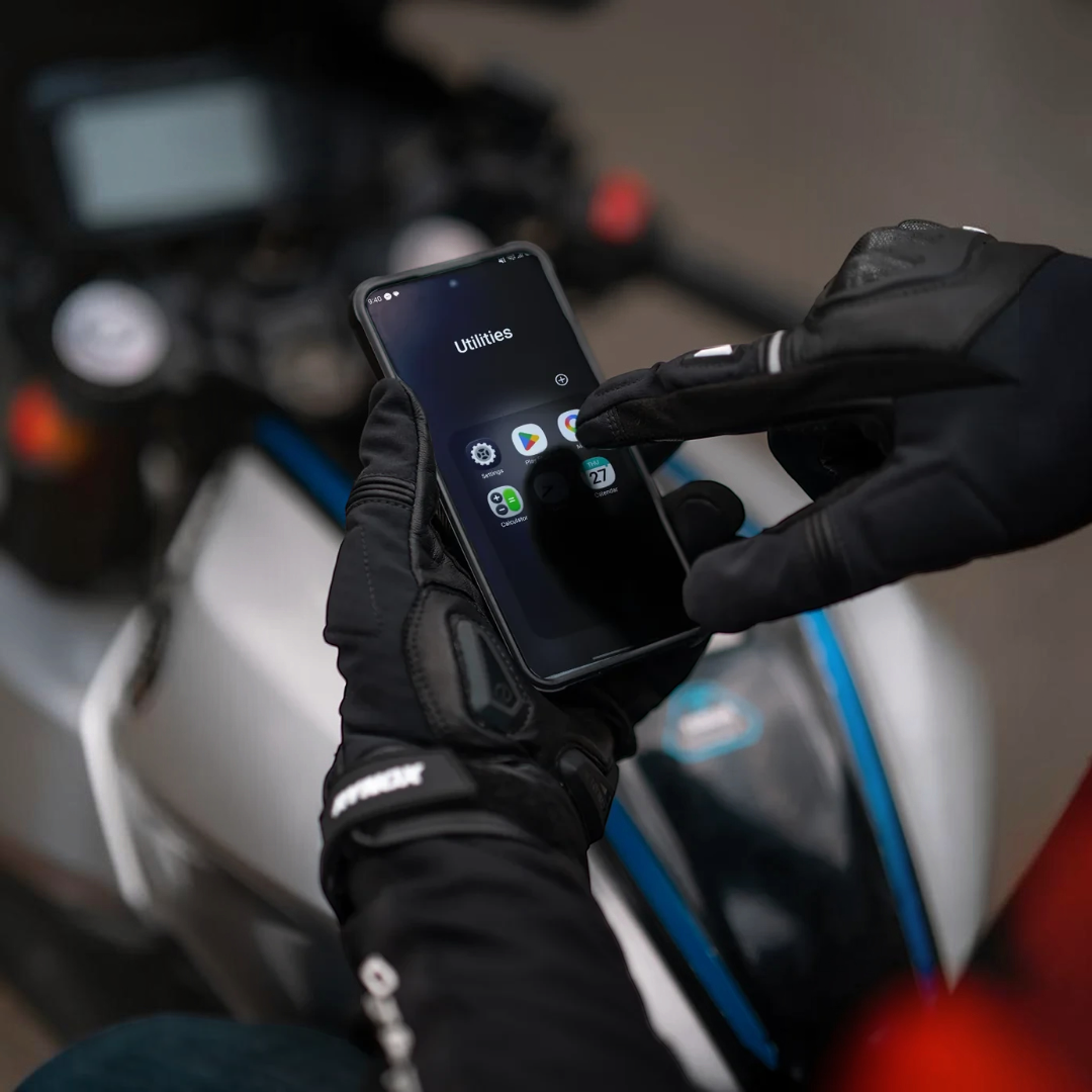 Motodrift Rynox Delta GT black leather motorcycle gloves with touchscreen-friendly fingers on a smartphone