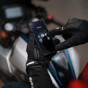Motodrift Rynox Delta GT black leather motorcycle gloves with touchscreen-friendly fingers on a smartphone