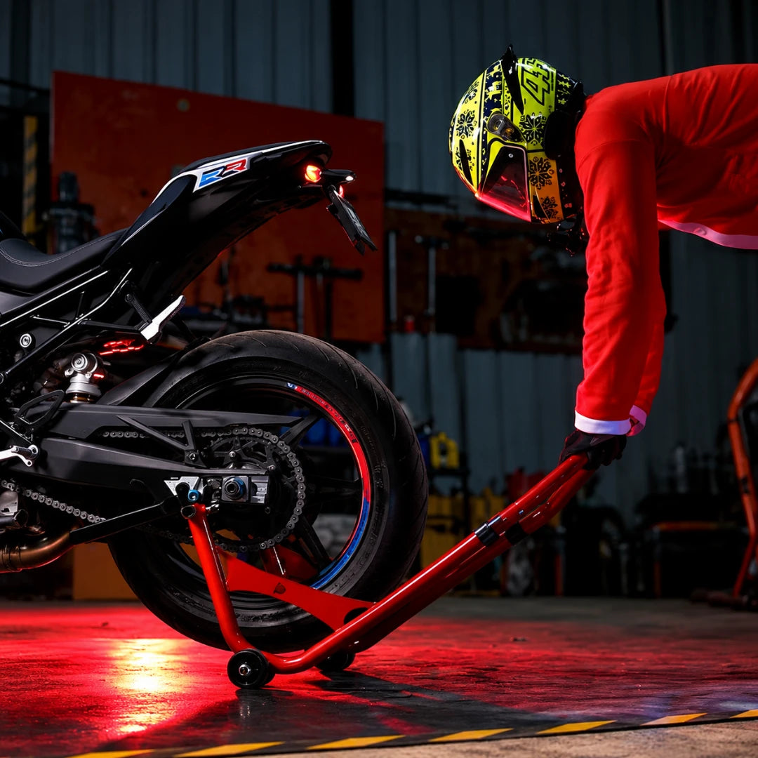RKTECH red universal motorcycle paddock stand lifting a bike in a workshop with a rider in a Santa suit