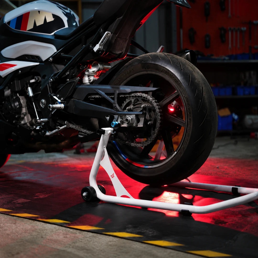 RKTECH white universal motorcycle paddock stand supporting a sportbike rear wheel in a workshop