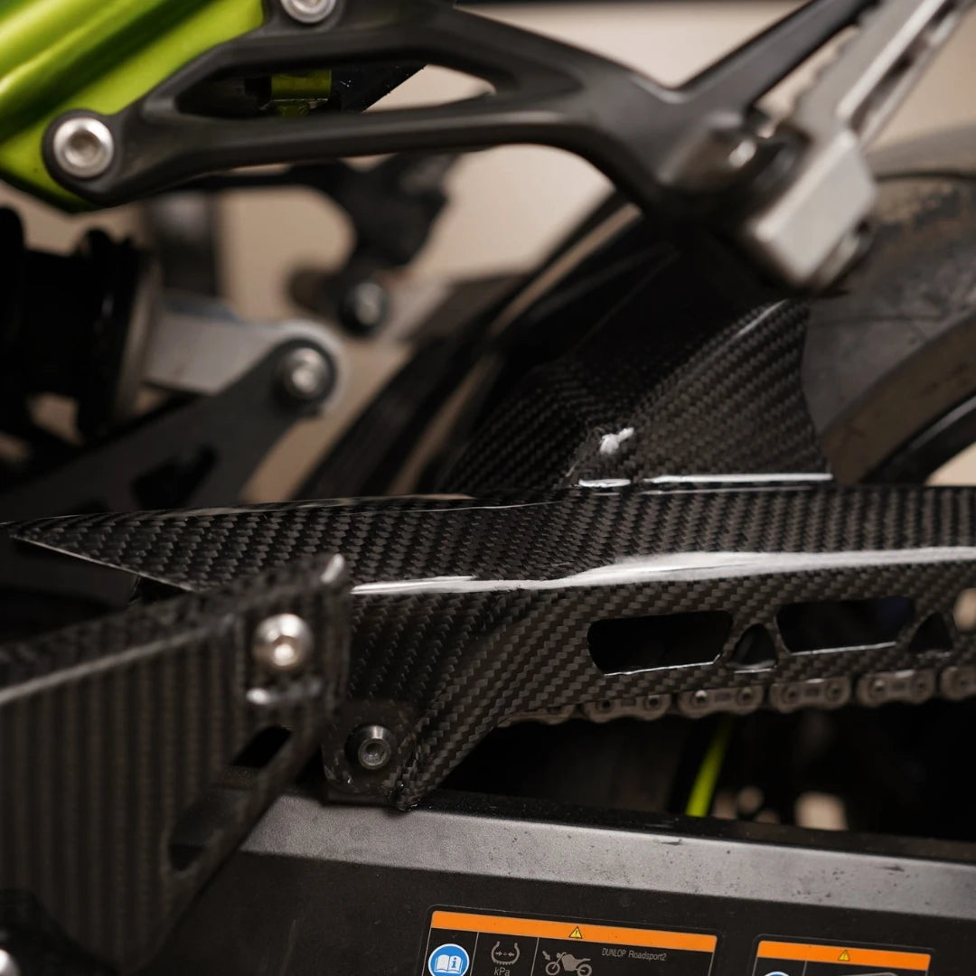Carbon fiber rear hugger with integrated chain guard in twill gloss finish for Kawasaki Z900 motorcycle.