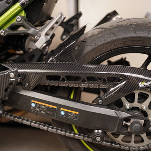 Carbon fiber rear hugger and chain guard with twill gloss finish installed on a Kawasaki Z900 motorcycle.