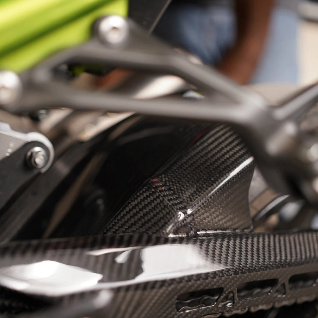 Carbon fiber rear hugger with integrated chain guard for Kawasaki Z900 in a glossy twill weave finish.